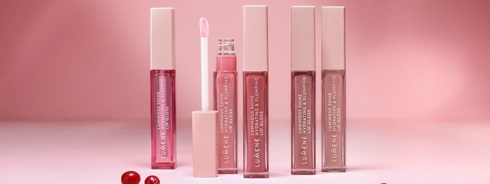 Nyhet: Lumene Luminous Shine Lip gloss i 5 ulike farger, rosa, lilla og bruntoner. På dekorativ rosa bakgrunn. 